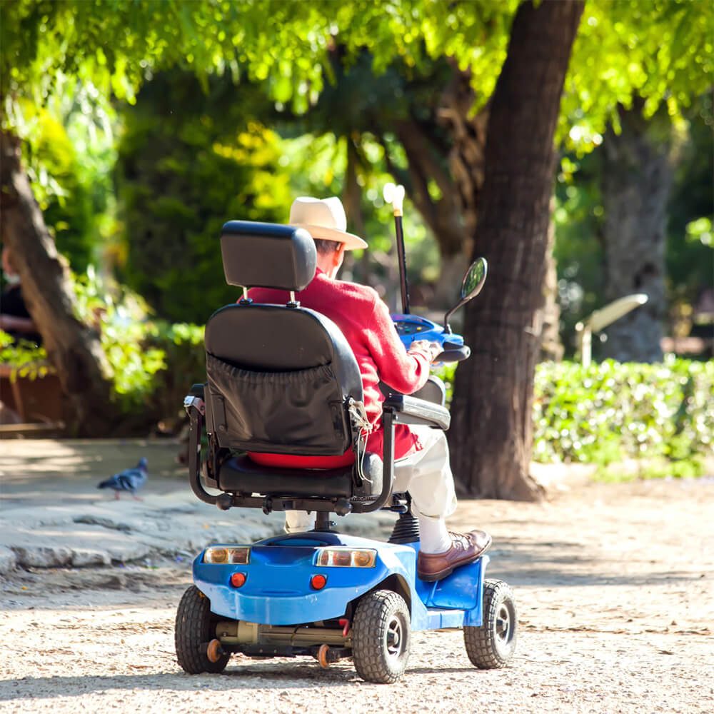 senior man driving a mobility scooter rental in the park